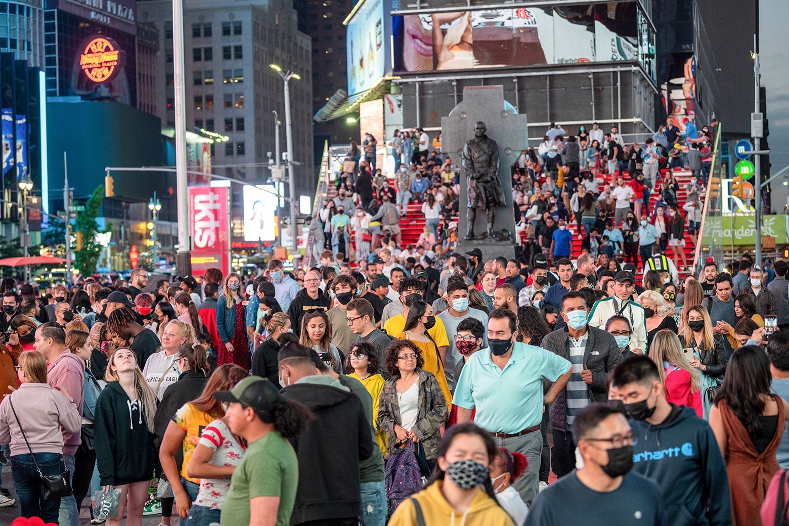Large crowds of people with and without masks fill Times Square.