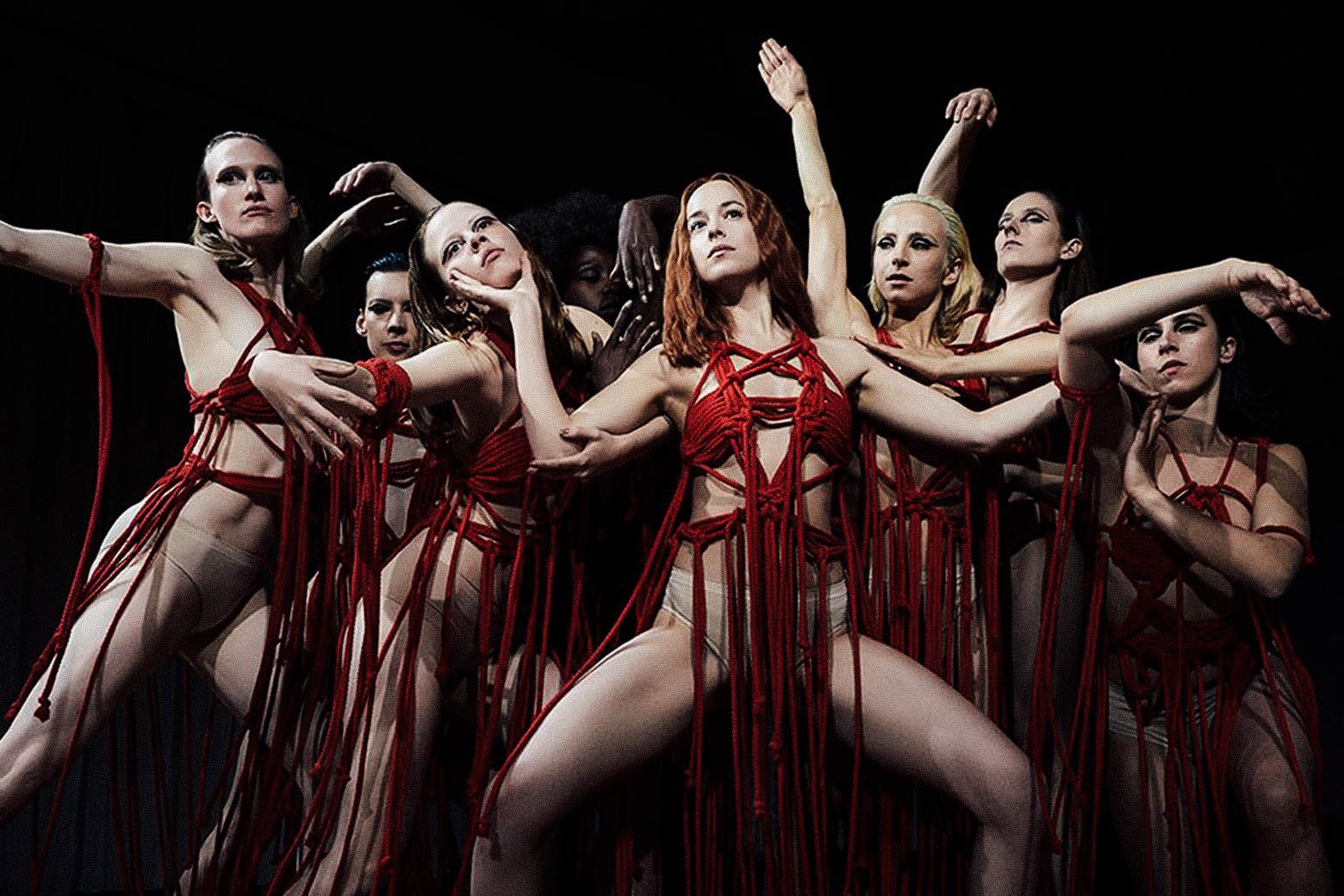 Dancers in red string outfits.