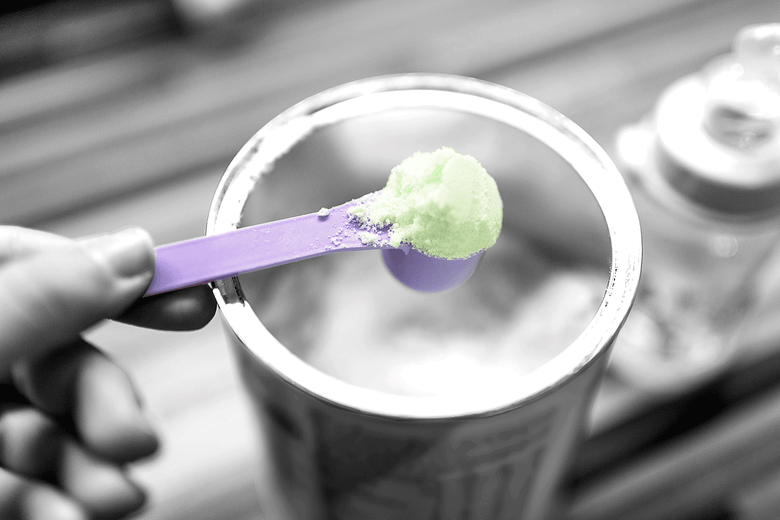 A purple spoon scoops formula out of a can.