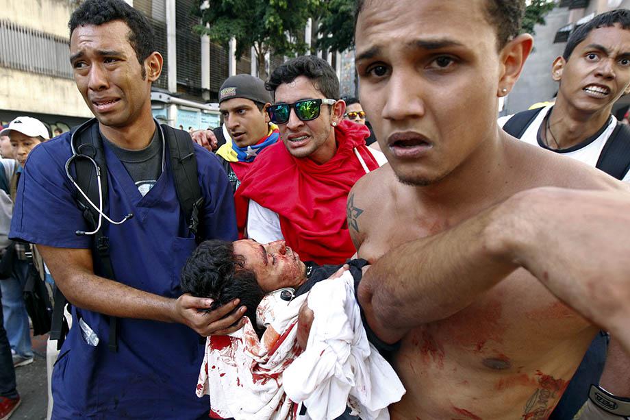 A dead protester is carried away on a motorcycle after gun shots were heard during an anti-government rally in Caracas.