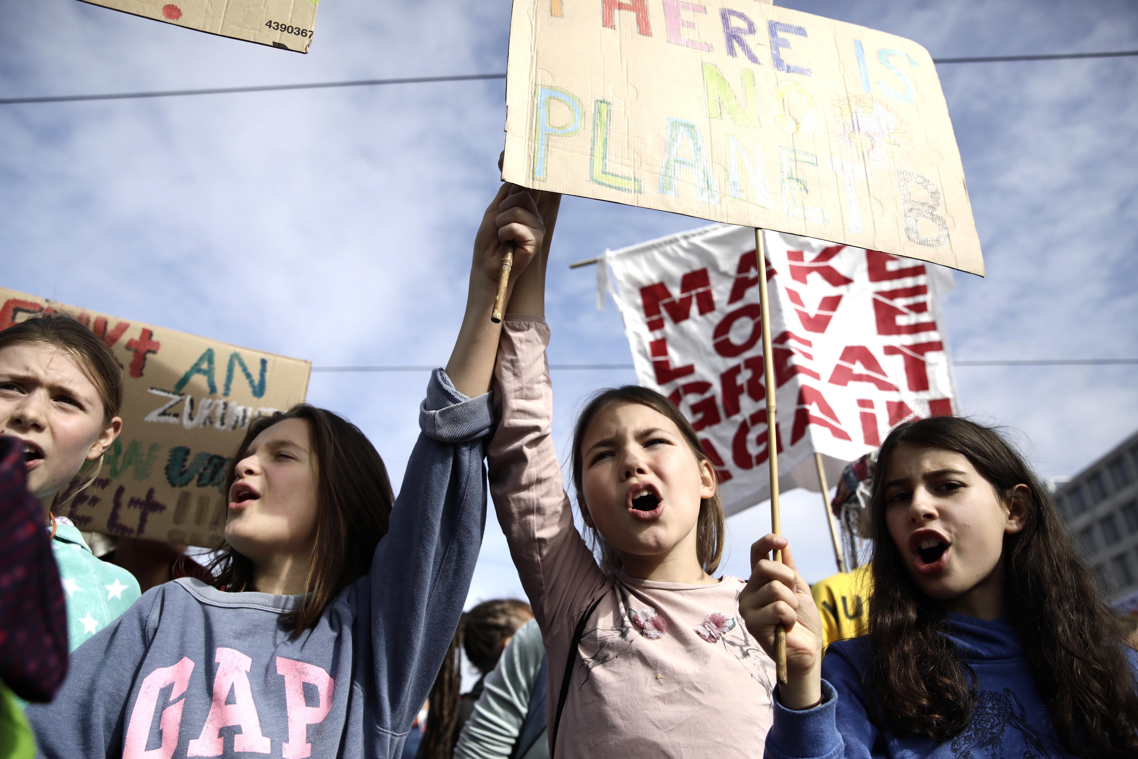 A group of girls chant and hold up signs.