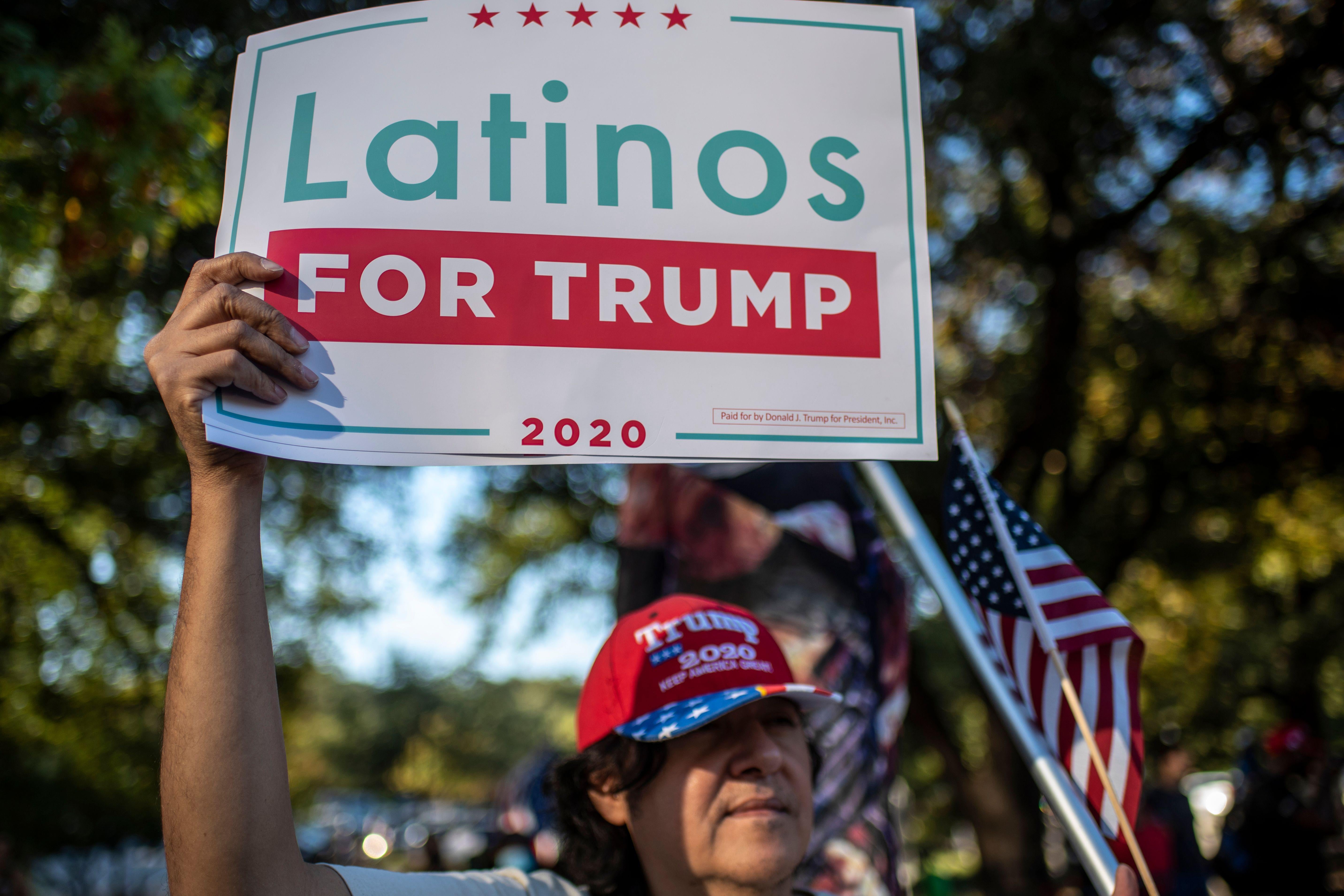 A man holds up a "Latinos for Trump" sign.