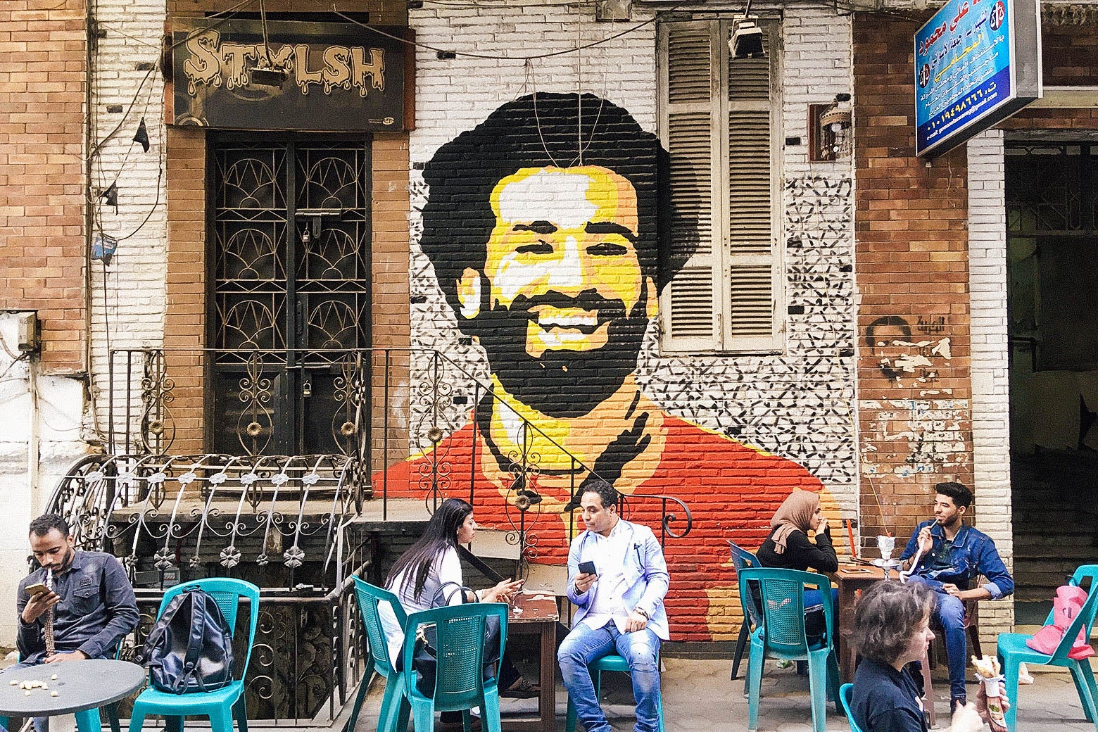 People sit at a café in downtown Cairo with a mural depicting Mohamed Salah in the background on April 4.