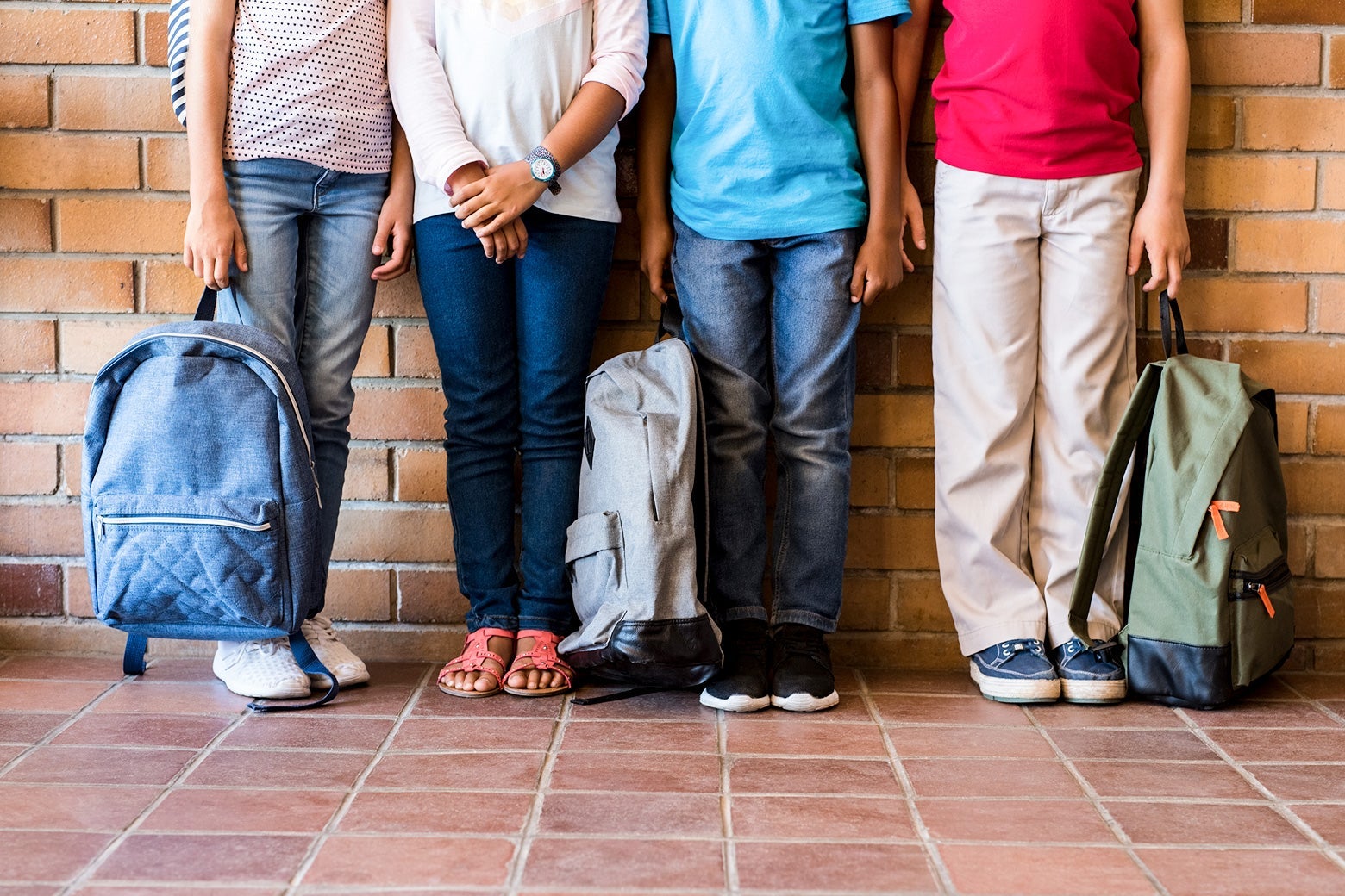 A row of kids holding backpacks.