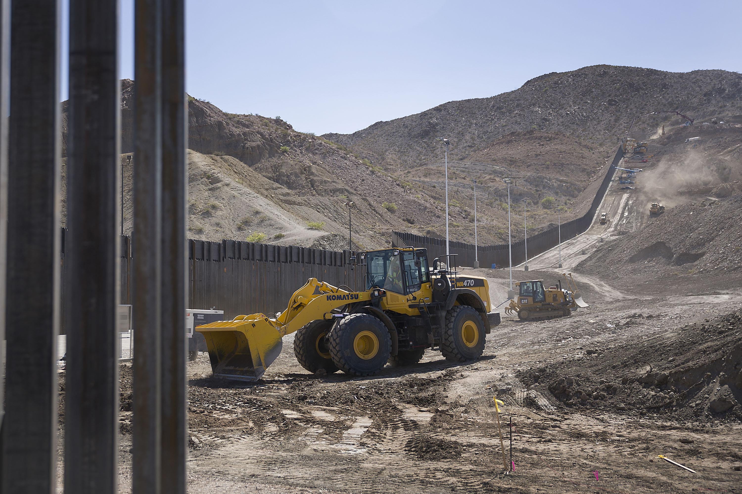 Construction crews work on a border wall.