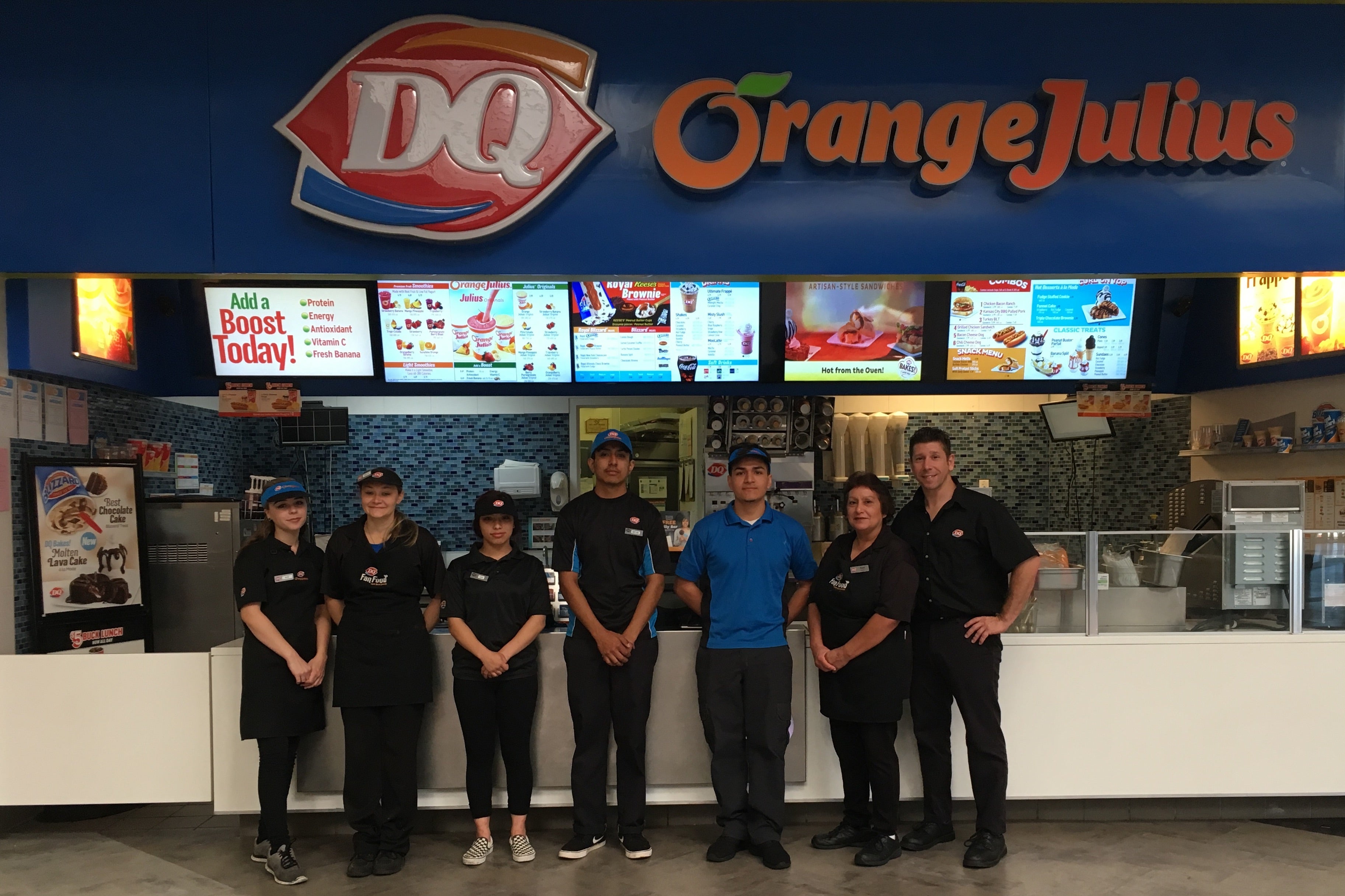 The staff of the Northridge Mall Dairy Queen, including franchise owner Rocco Frattaroli. They are posing in front of the location and the sign, as well as an Orange Julius sign.