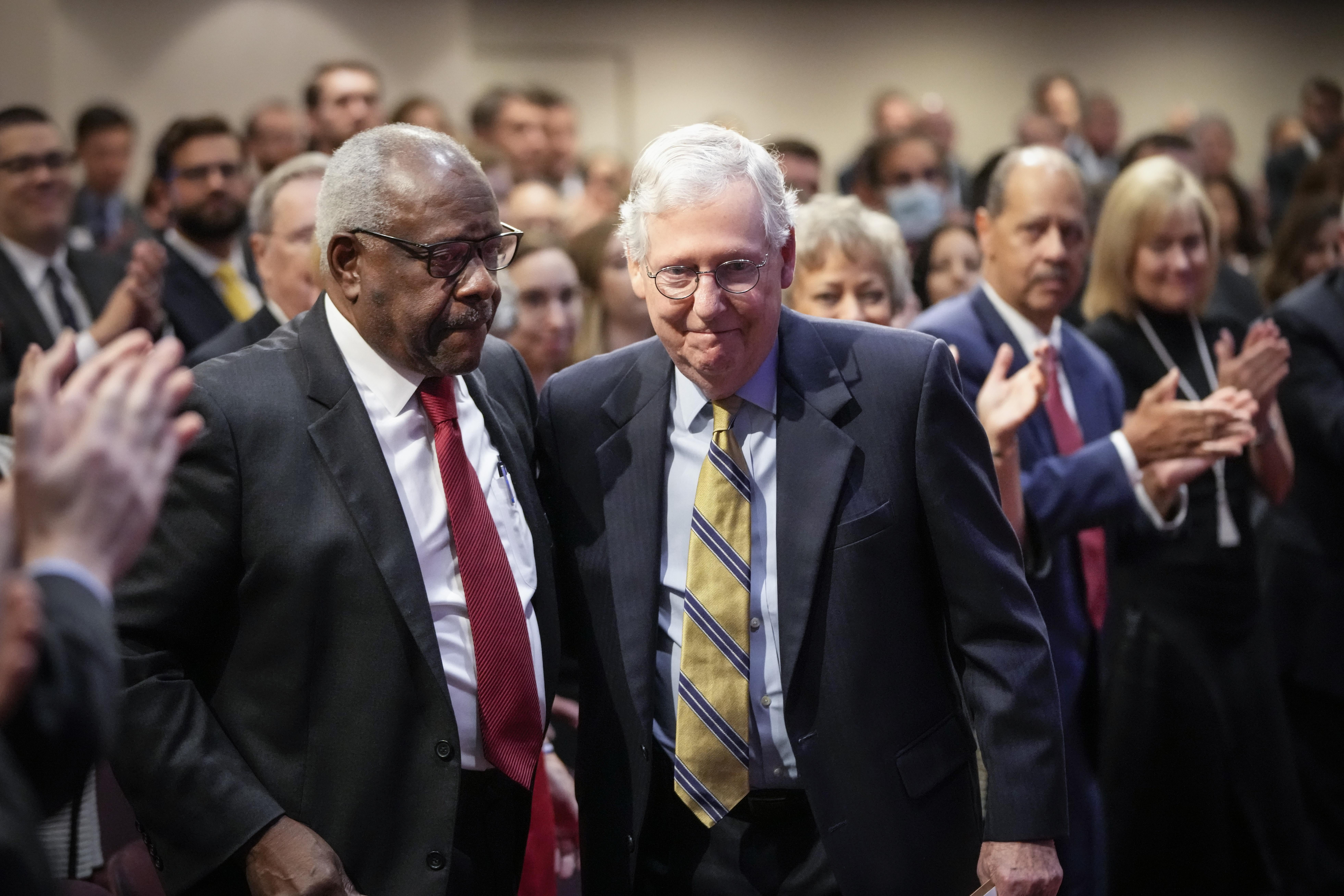 Thomas and McConnell standing close to each other in a crowded room of people clapping