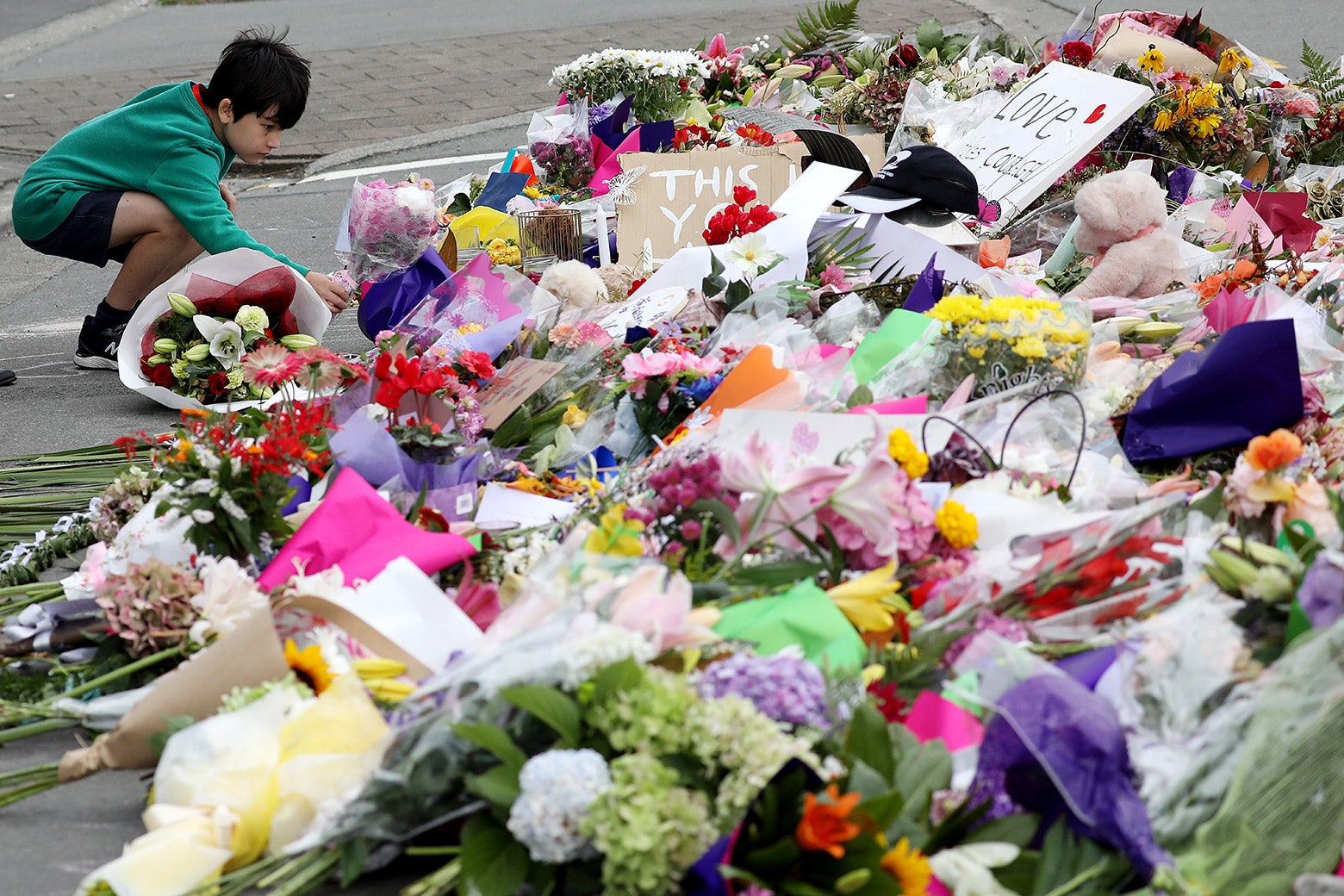 A little boy places flowers at a memorial to the Christchurch shooting victims.