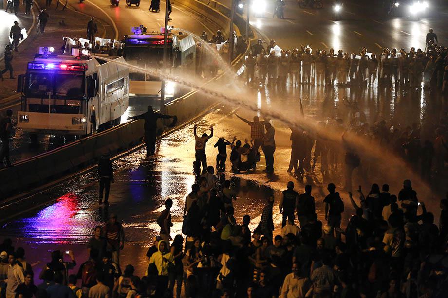 Riot police use water to disperse opposition demonstrators as they block the city's main highway during a protest against Nicolas Maduro's government in Caracas.