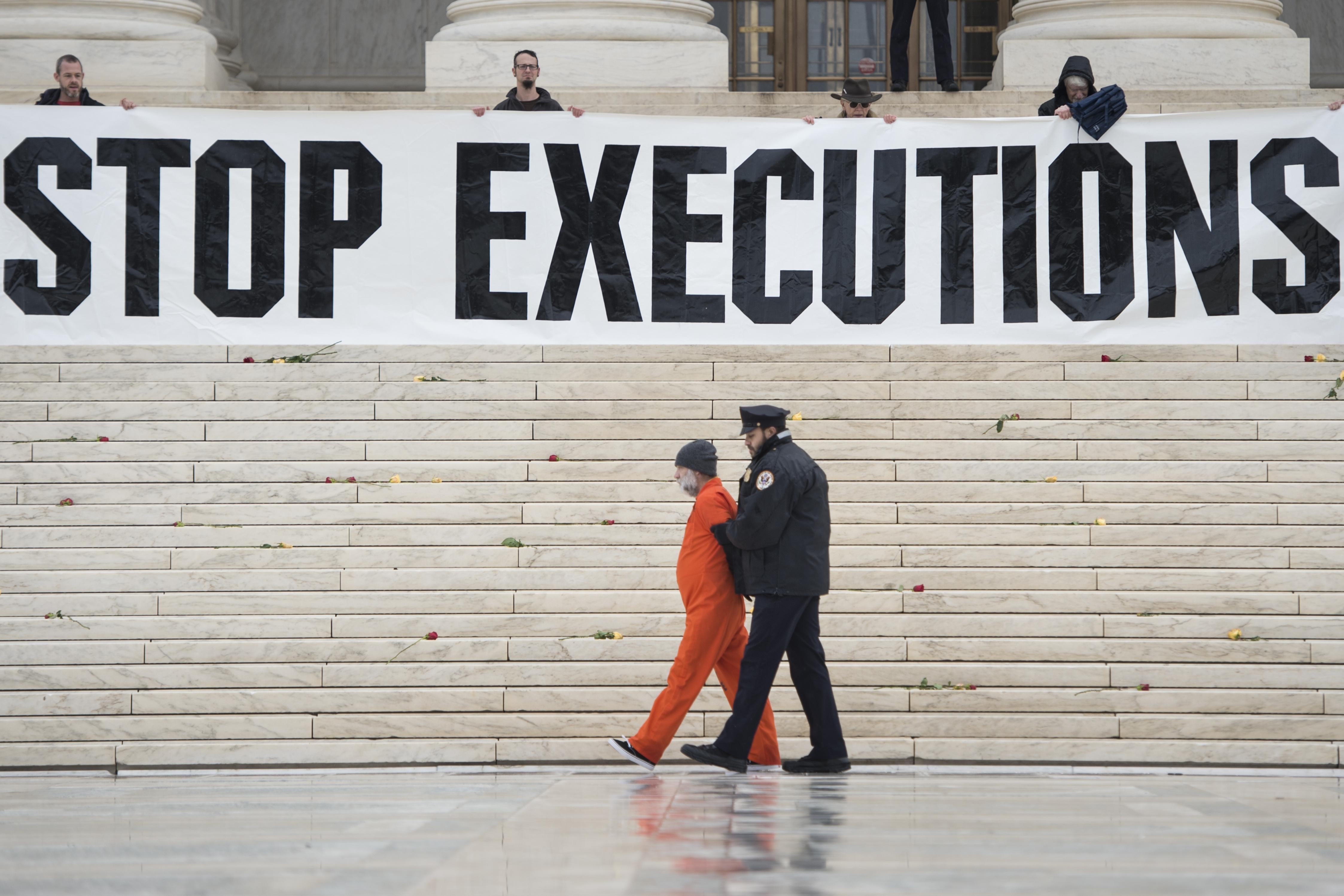 A police officer marches a man in an orange jumpsuit away from the building. Above, on the Supreme Court steps, protesters stand behind a banner that reads STOP EXECUTIONS.