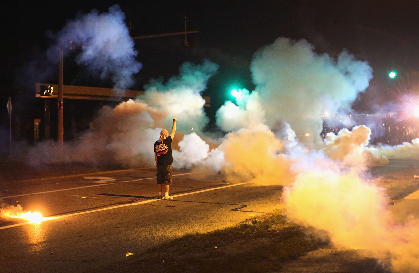 A demonstrator, protesting the death of teenager Michael Brown, stands his ground as police fire tear gas on August 13, 2014 in Ferguson, Missouri. 