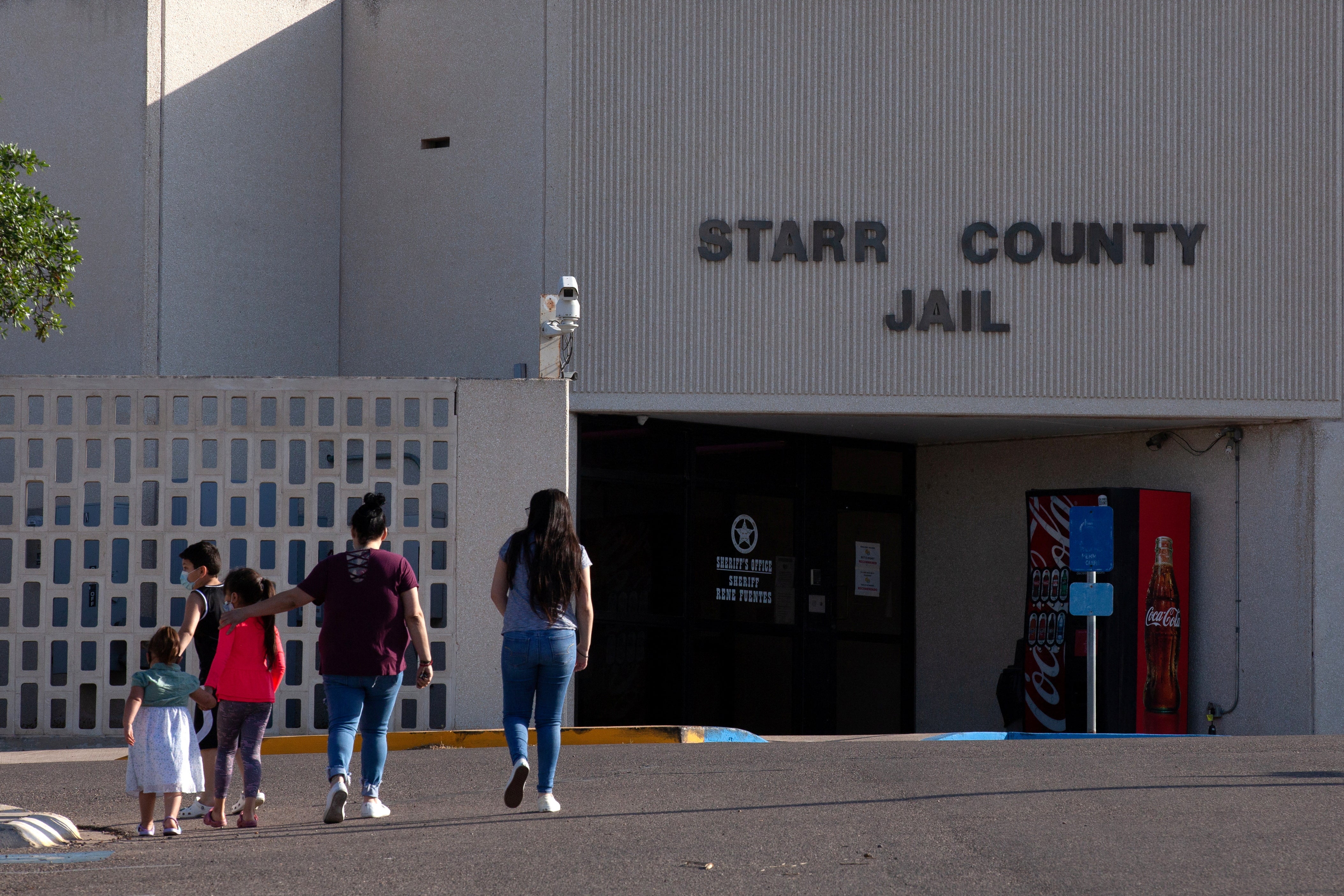 A woman and four children walk toward the entrance of a building labeled as the Starr County Jail.