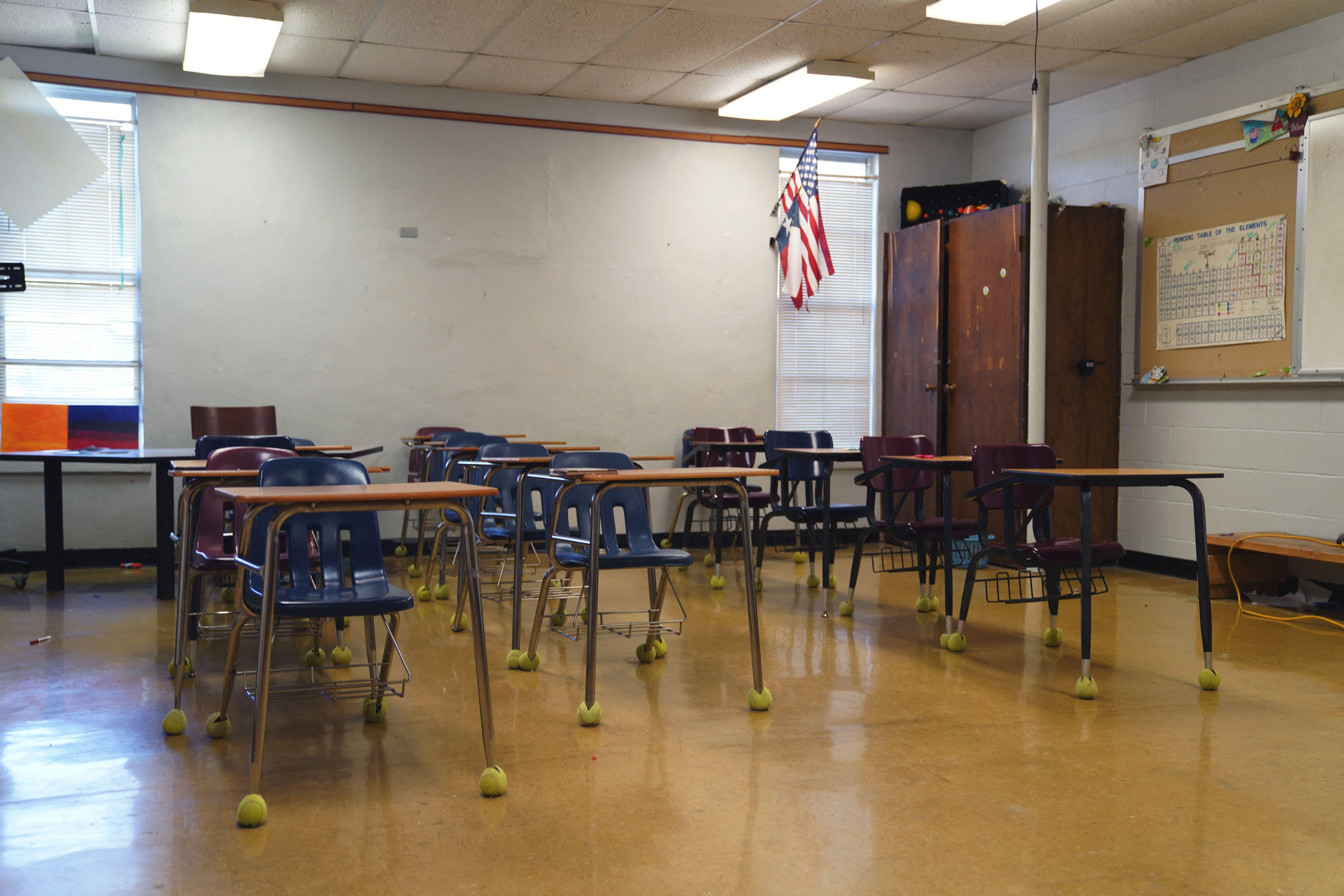 An empty school classroom with desks, chairs, and a whiteboard