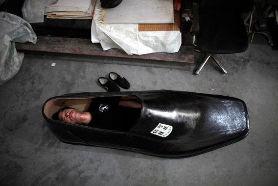 Chen Mingzhi, a shoe designer, lies inside of his handmade 1.9 meter-long (6.23 foot-long) right shoe at his family store in Wenling, Zhejiang province in September 2012.