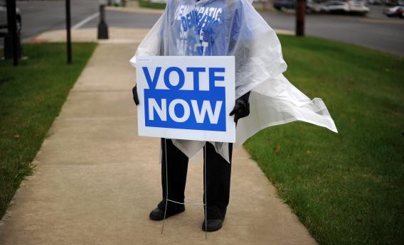 An Ohio Democratic Party volunteer displays a placard to encourage public for early voting in front of an early voting center.