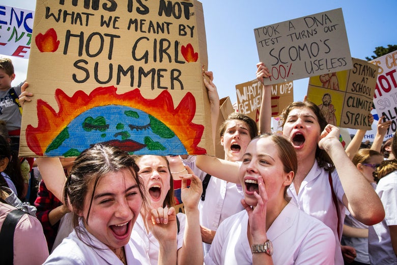 Students shout while one holds a sign saying "this is not what we meant by hot girl summer."