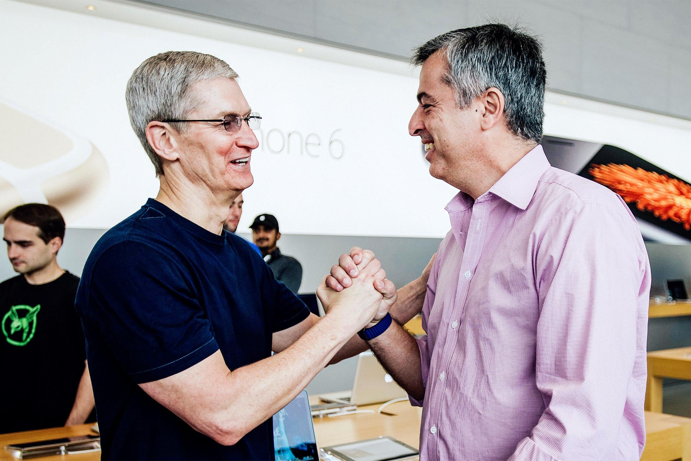 Tim Cook shakes Eddy Cue’s hand in a sort of arm wrestling pose at an Apple Store for the iPhone 6 launch.