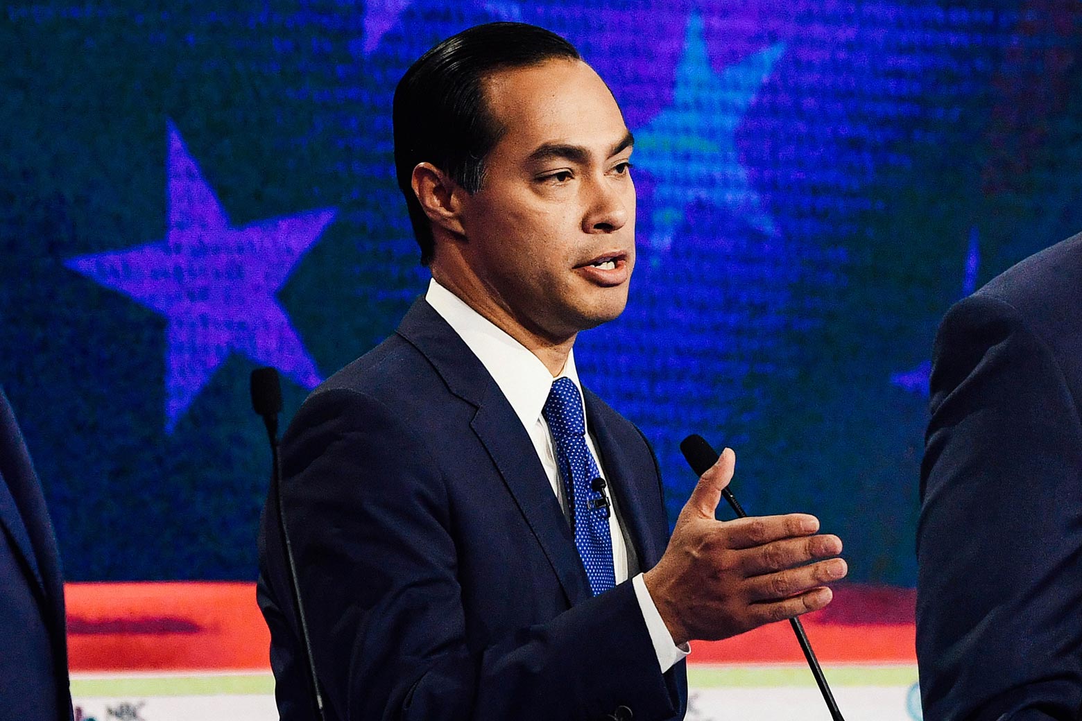 Julián Castro gestures from behind his podium on the debate stage.