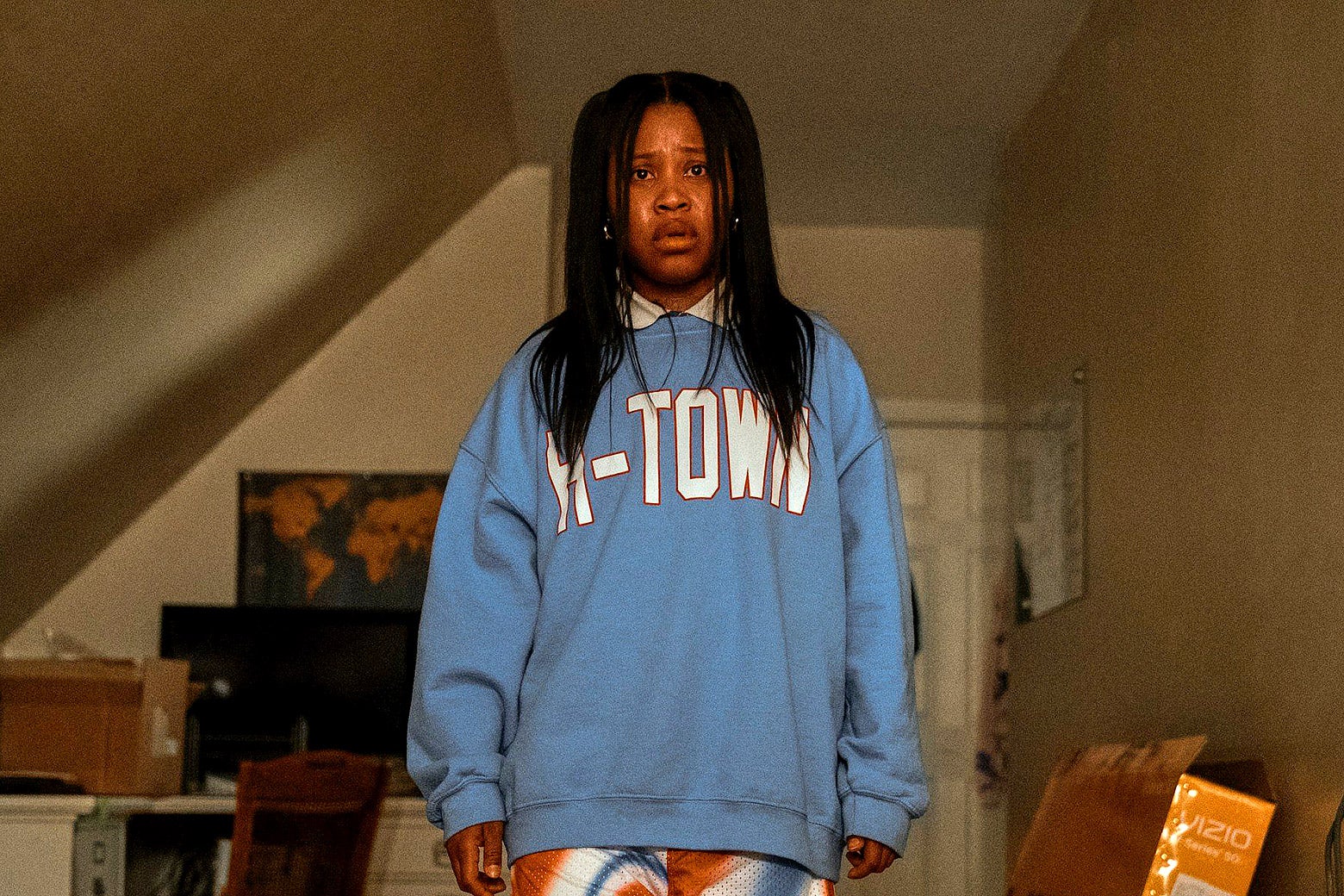 A woman in a sweatshirt that reads "H-Town" stands in a room. 