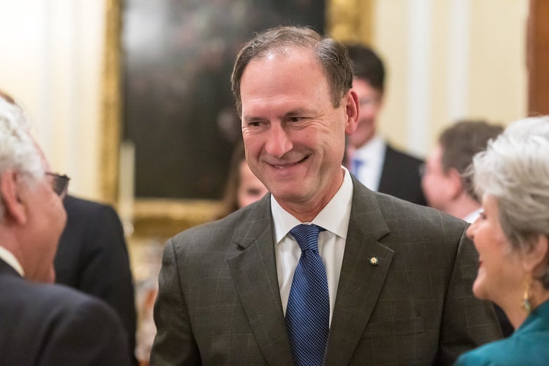 Justice Samuel Alito wearing a suit and tie and grinning