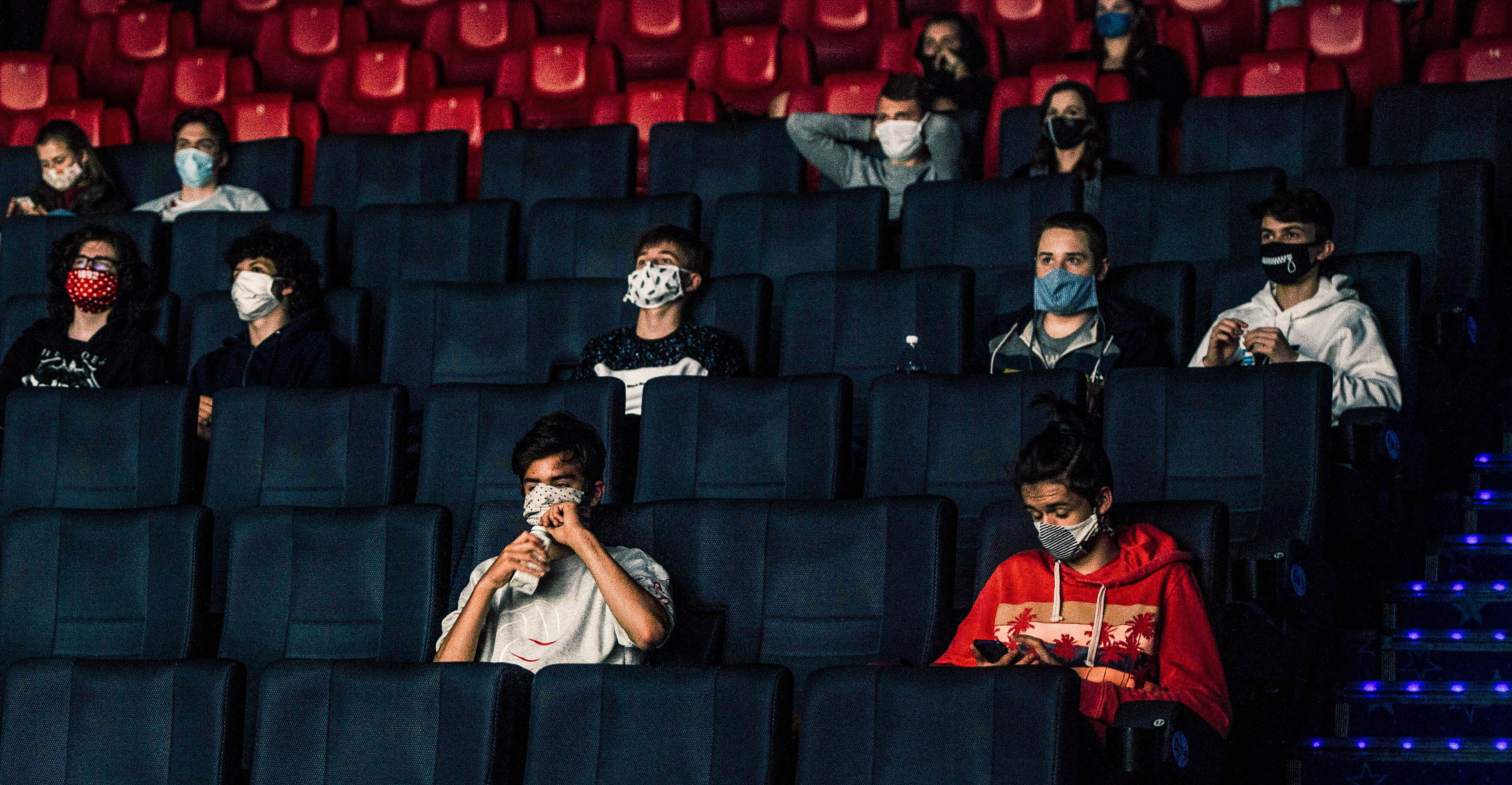 People wearing masks inside of a movie theater.