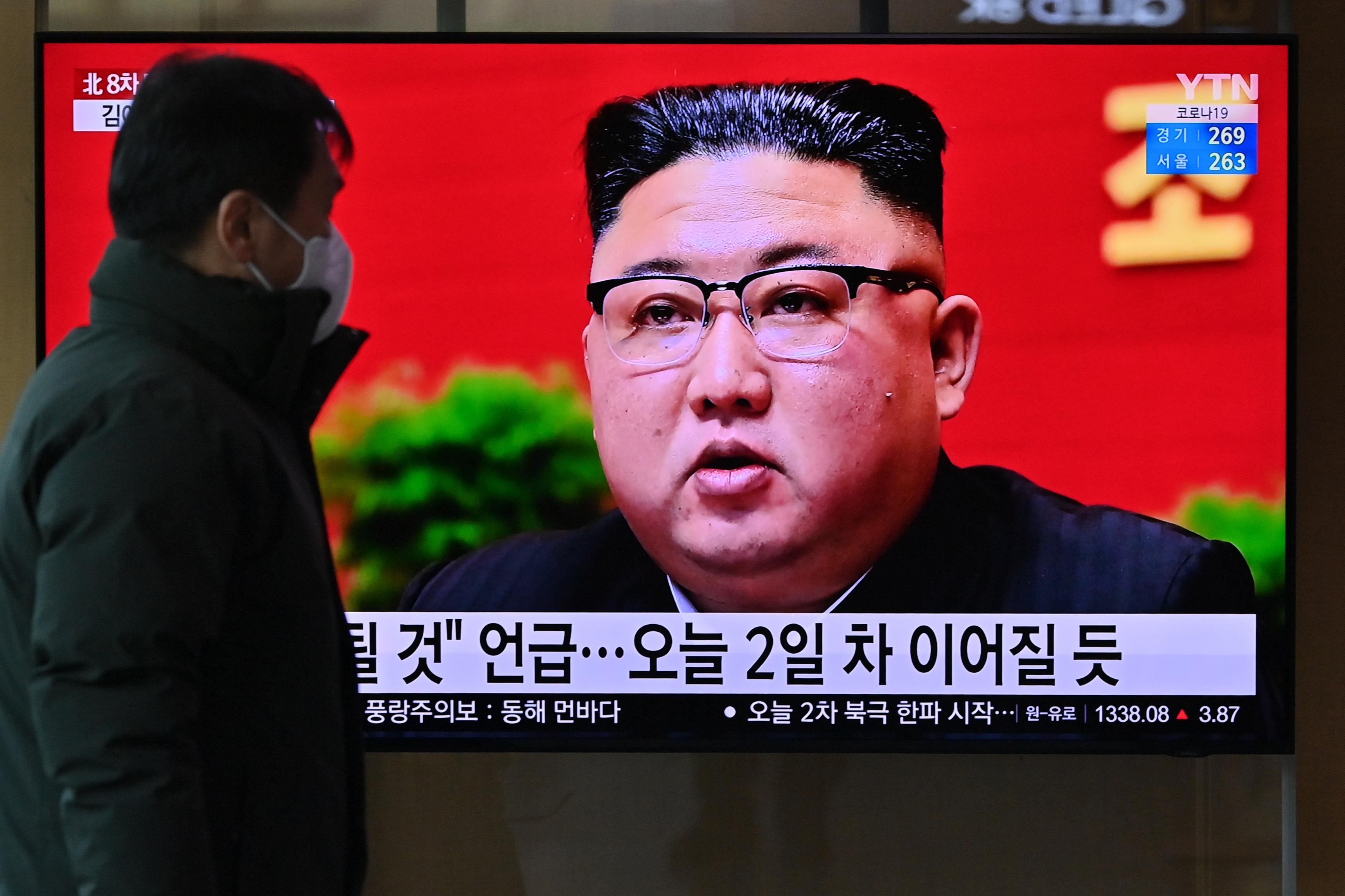 A man watches a television screen showing news footage of North Korean leader Kim Jong Un.