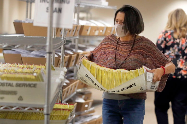 An election worker carries mail-in ballots in U.S. Postal Service containers.