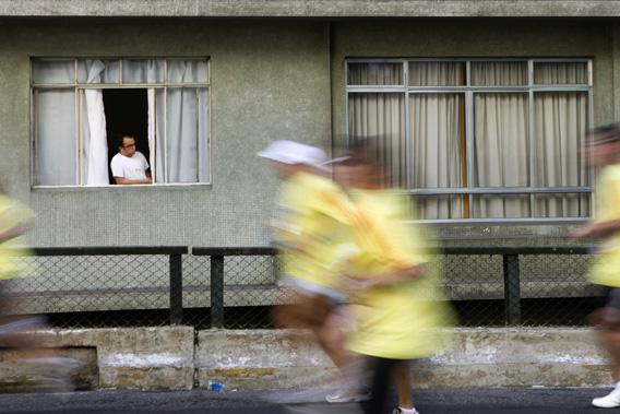 A resident looks out from a window of his apartment at people running during the Virada Esportiva program in Sao Paulo, July 1, 2012.