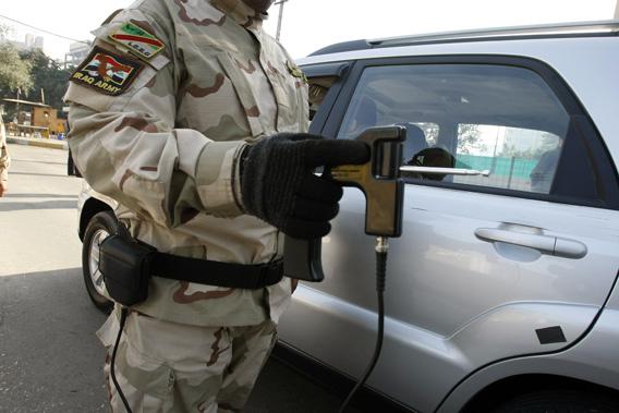 An Iraqi soldier walk along side a car as he holds a "bomb detecting device" at a checkpoint in central Baghdad on Jan. 23, 2010.