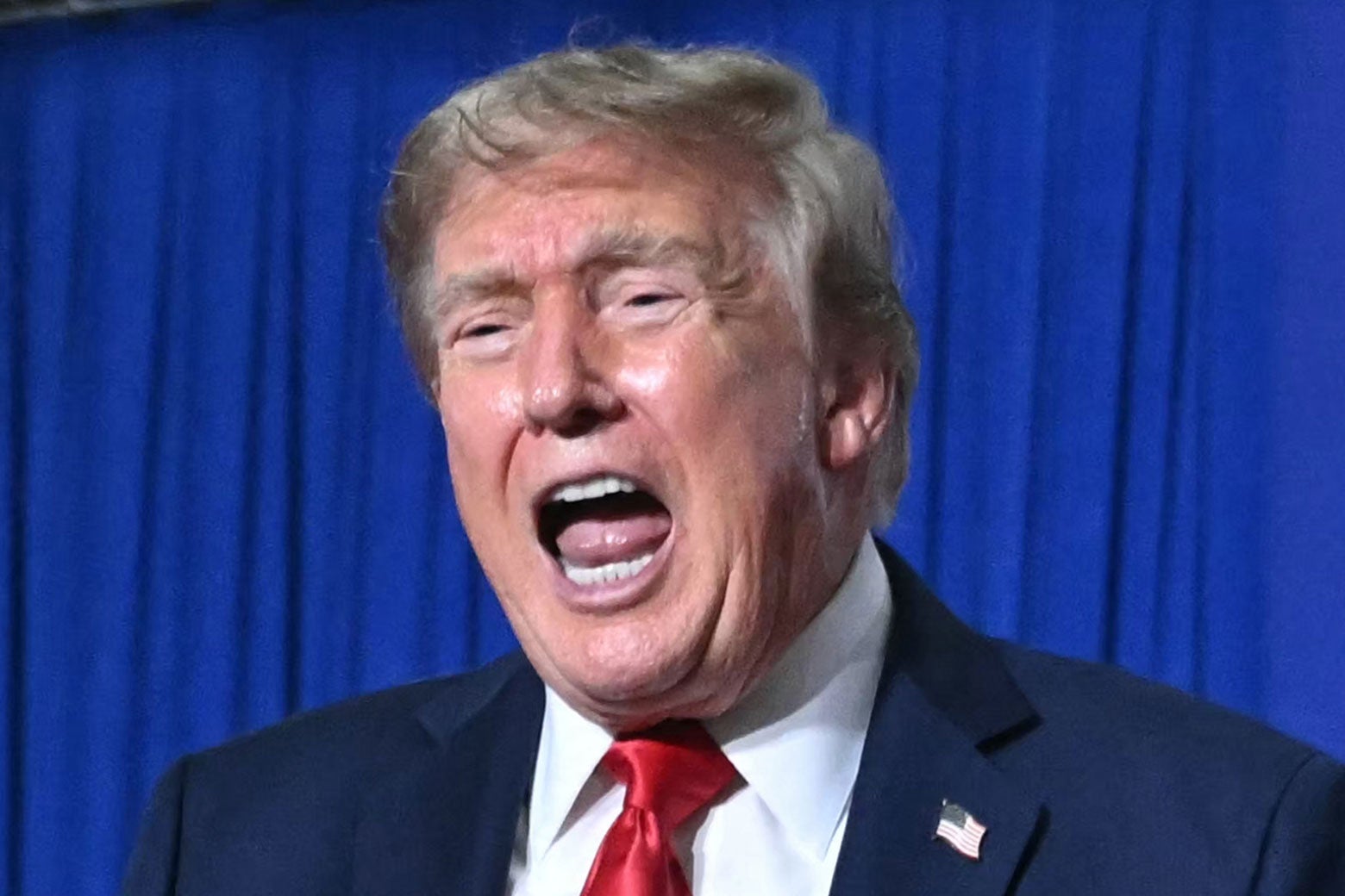 Donald Trump opens his mouth wide while speaking.