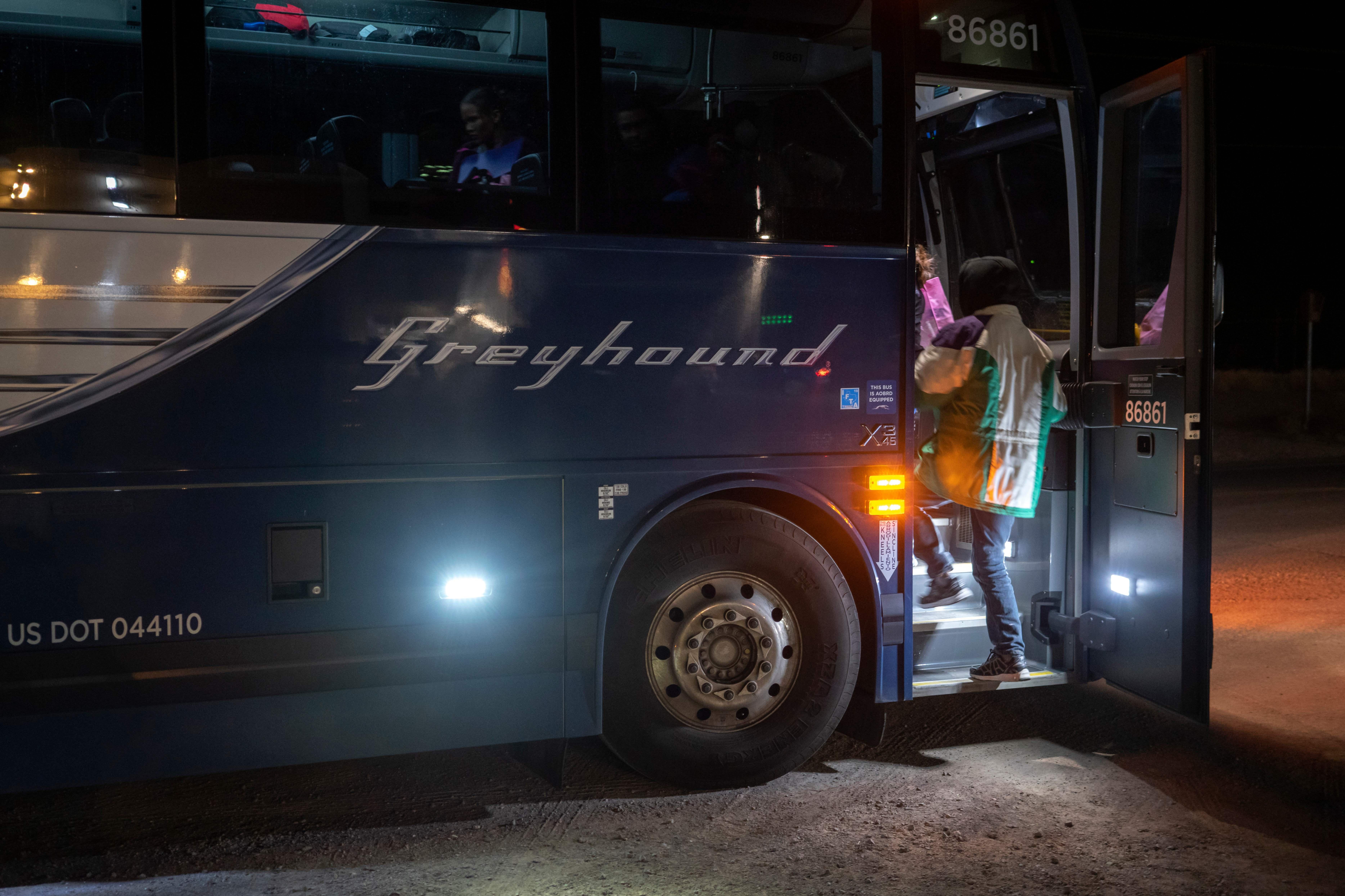 Two passengers board a Greyhound bus.