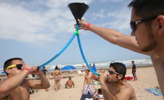 Students from the University of Texas at El Paso drink beer from a funnel on the beach during the annual ritual of Spring Break March 25, 2008 on South Padre Island, Texas.
