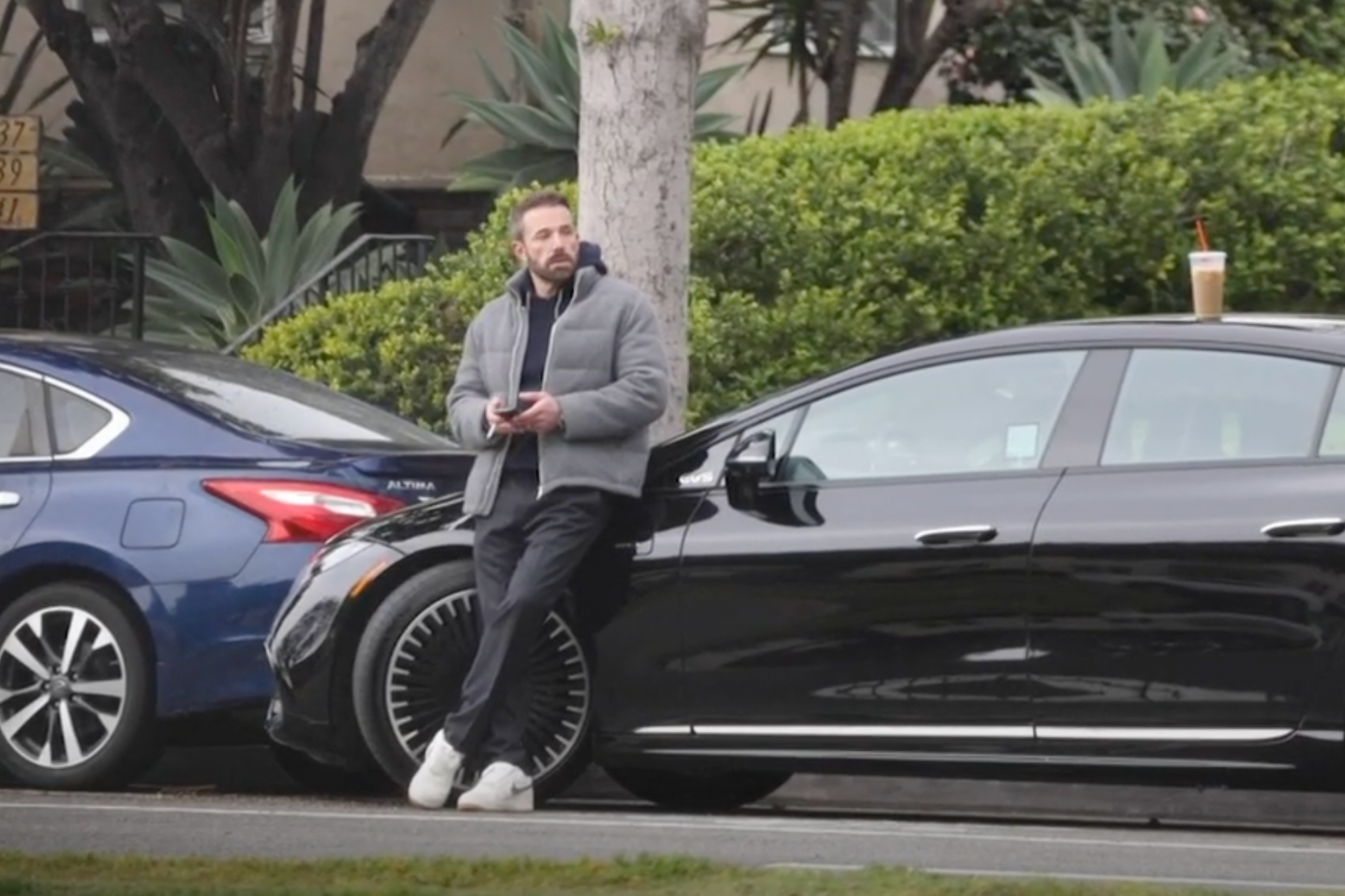 Ben Affleck is seen standing by his car with a coffee and cigarette, about to parallel park. 