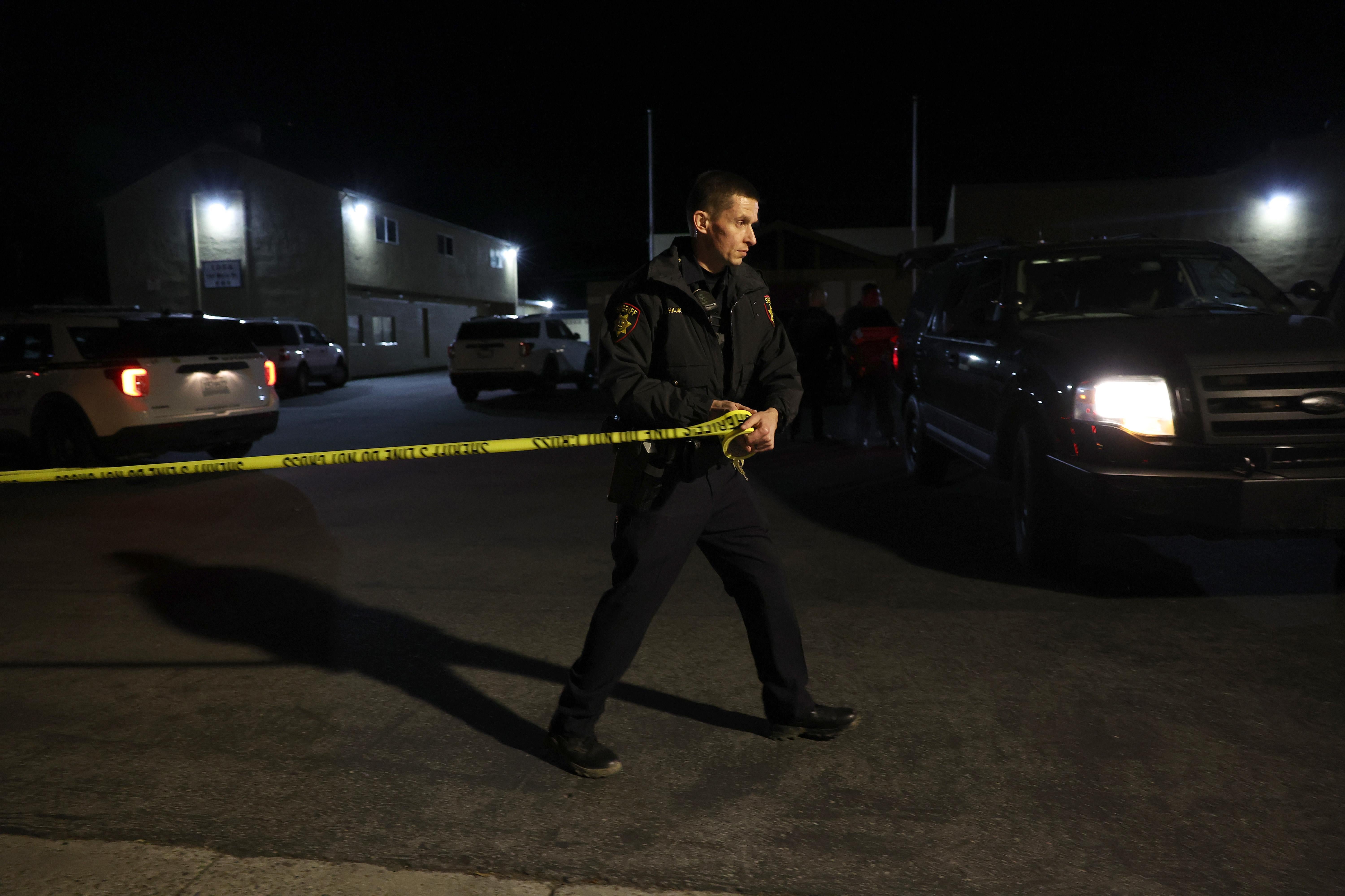 A sheriff pulls police tape across the entrance to a family reunification center.