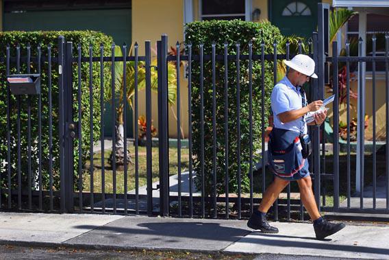 A mailman for the U.S. Postal Service delivers mail on Nov. 15, 2012, in Miami.