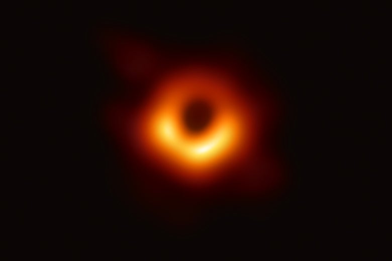 The photo of the black hole. It appears as a blurry ring of red and yellow light, dimmer on one side, with a flare of light radiating from that ring.