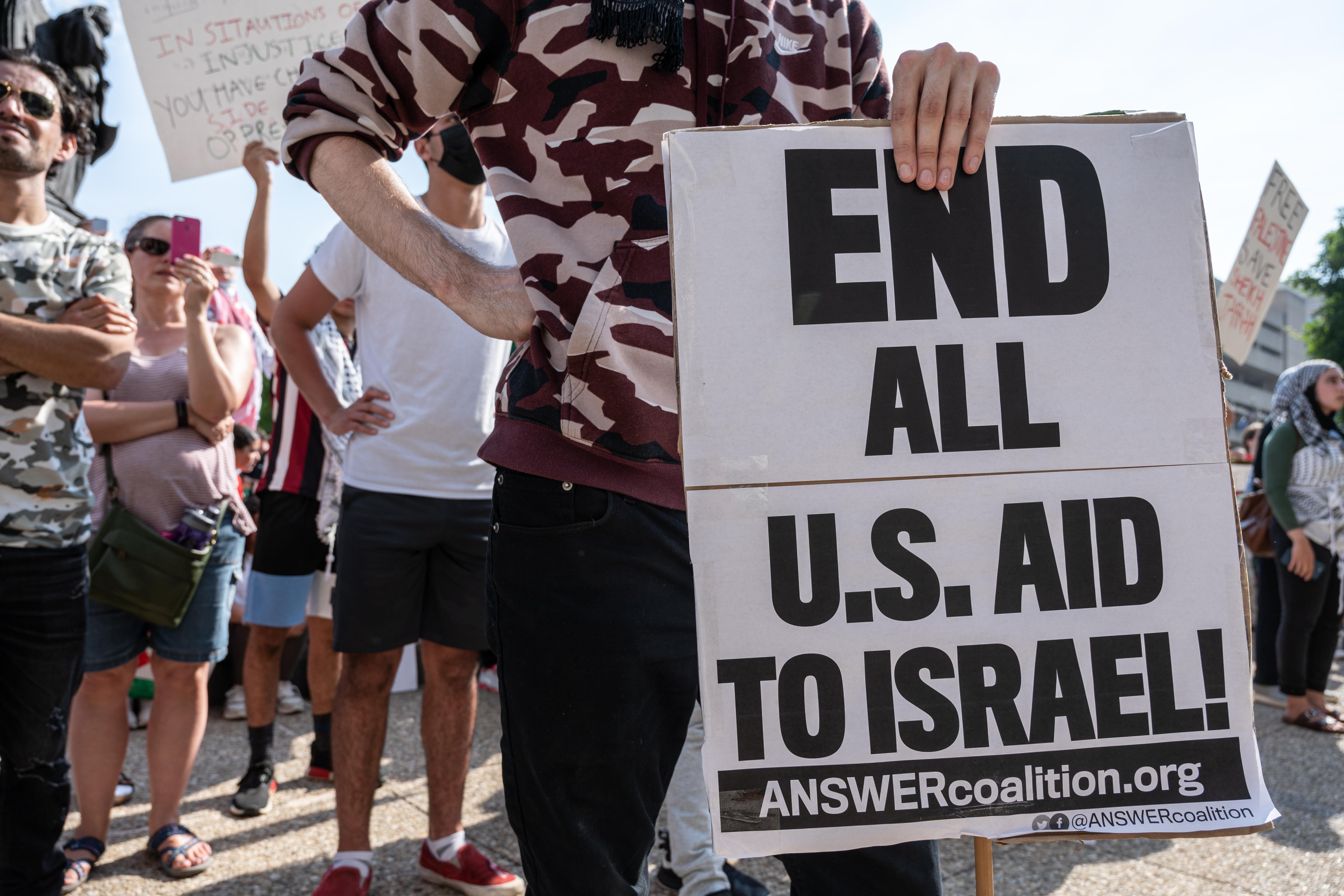 A man holds a sign that says, "End all U.S. aid to Israel."