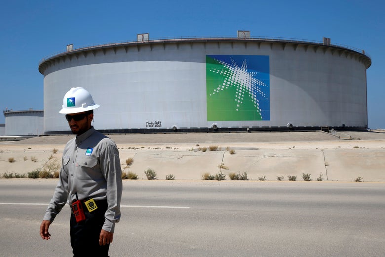 A ban in front of an oil tank with the Aramco logo on it.