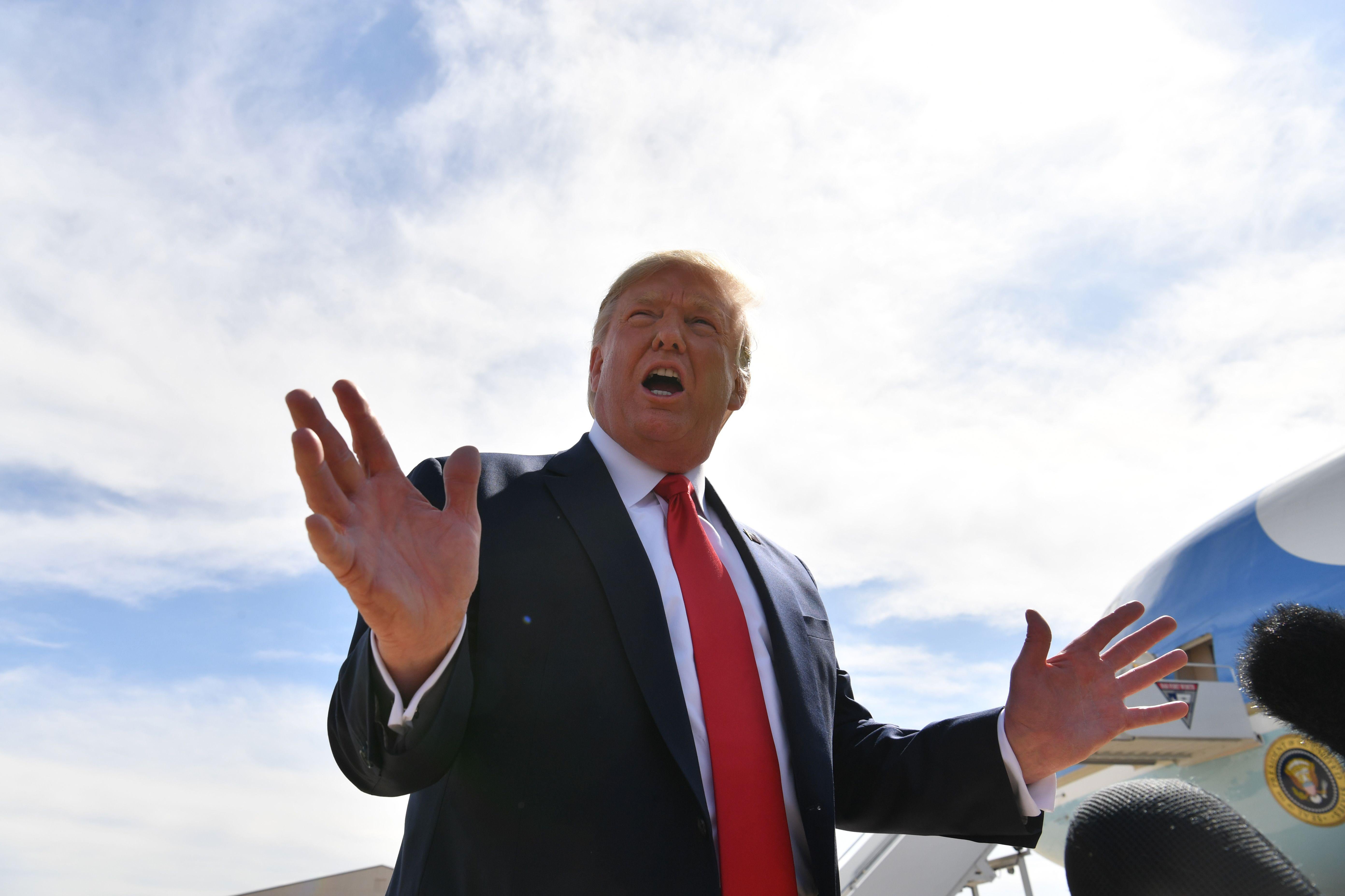 Trump speaking and gesturing, with Air Force One in the background.