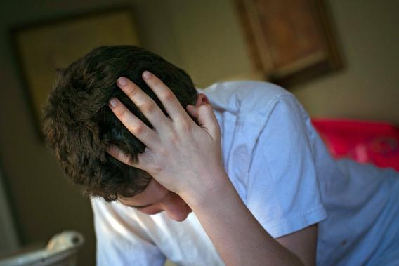 Matthew Kolen, who was diagnosed at age eight with Asperger's syndrome, puts his hand over his head while doing his homework in Long Island, New York April 16, 2012.  Matthew's diagnosis will soon redefined into the broader category of autism spectrum disorder in the fifth edition of the Diagnostic and Statistical Manual of Mental Disorders or DSM-5.