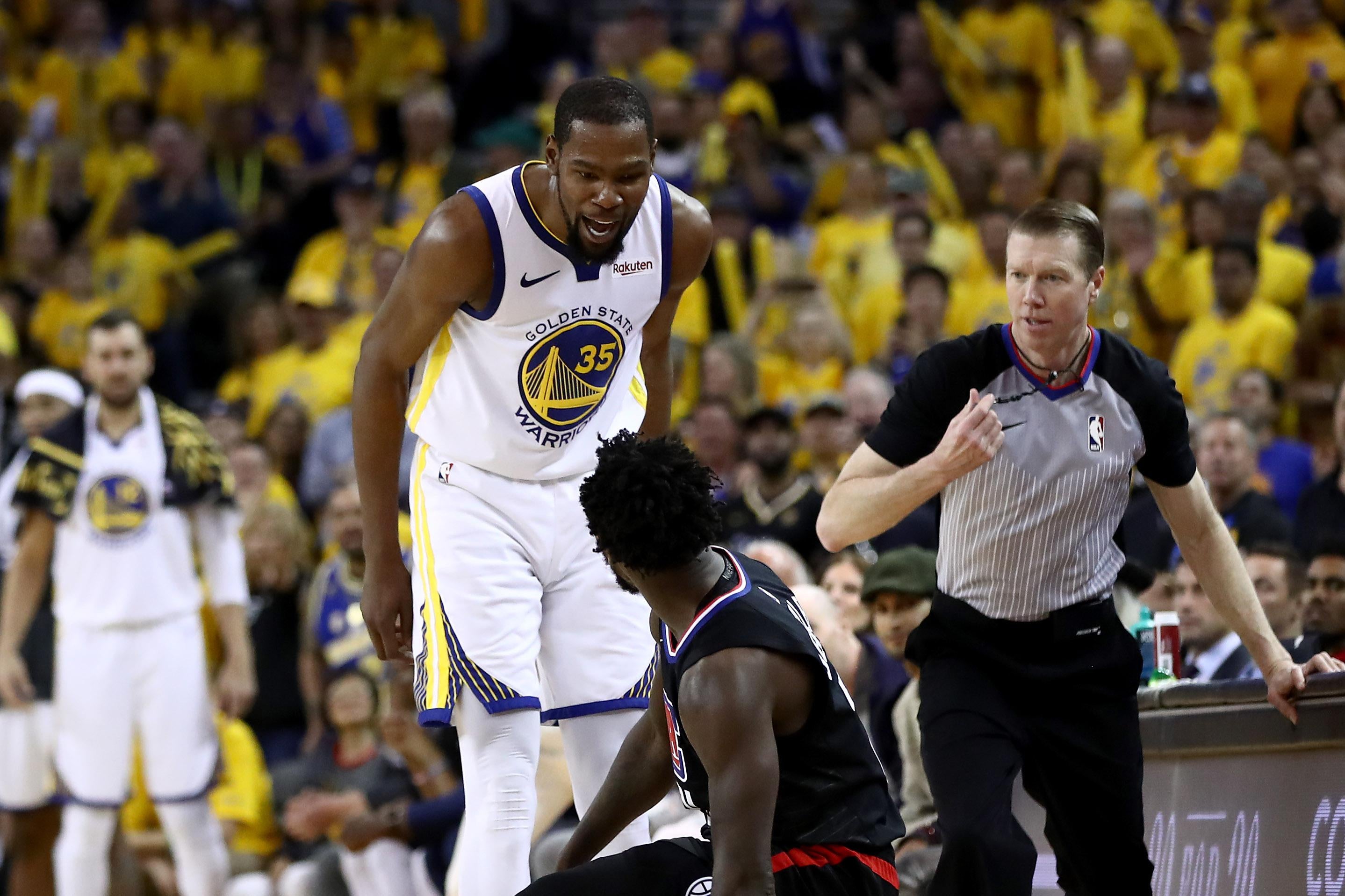 Kevin Durant stands over Patrick Beverley, who has fallen on the court. A ref moves to intervene.