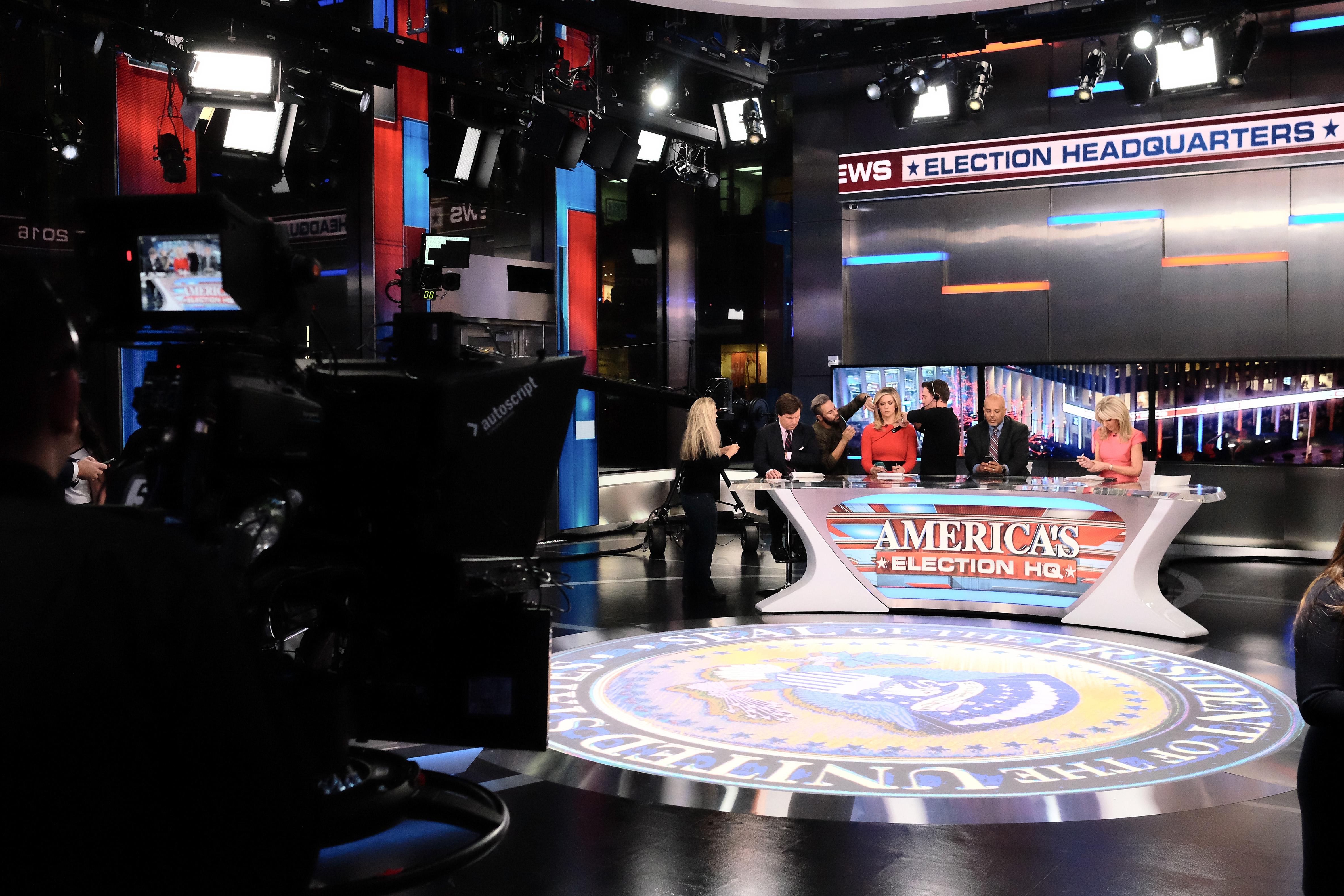 A TV studio set up for election night coverage, with pundits sitting behind a desk