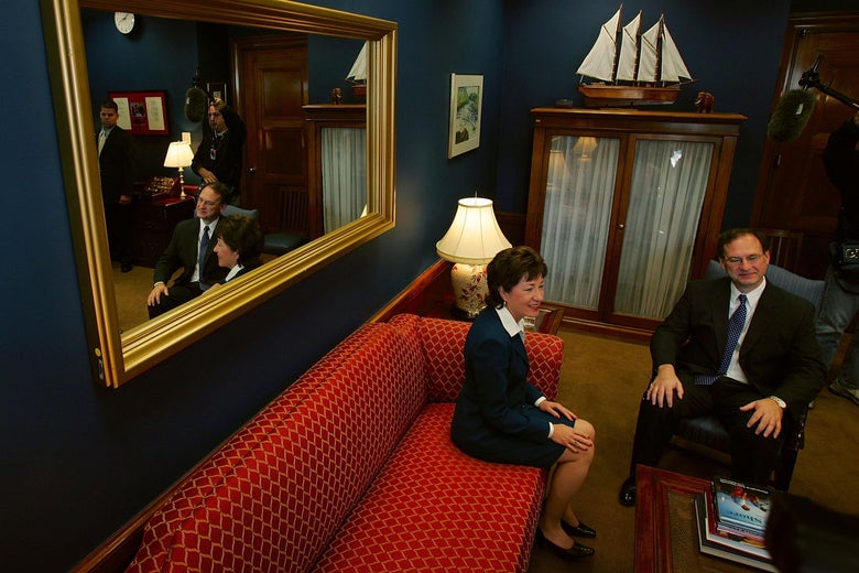 Alito sits in a chair next to Collins sitting on a red couch in a traditionally decorated Capitol room
