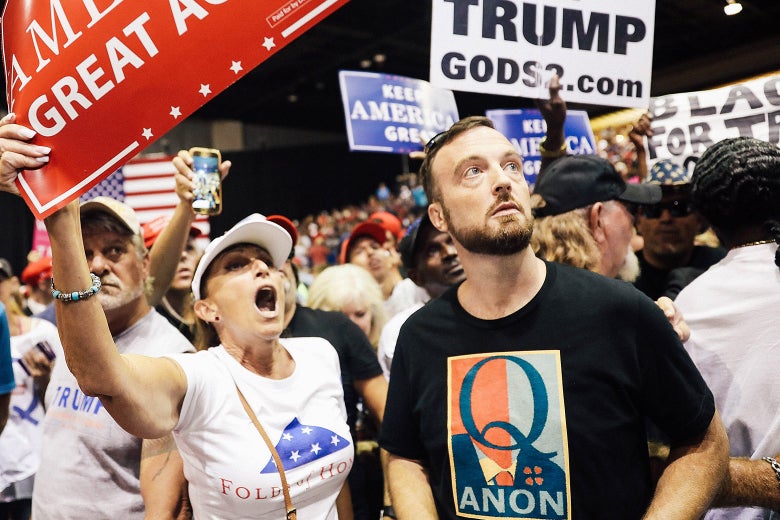 A man wearing a QAnon T-shirt stands amid the crowd at a Trump rally.
