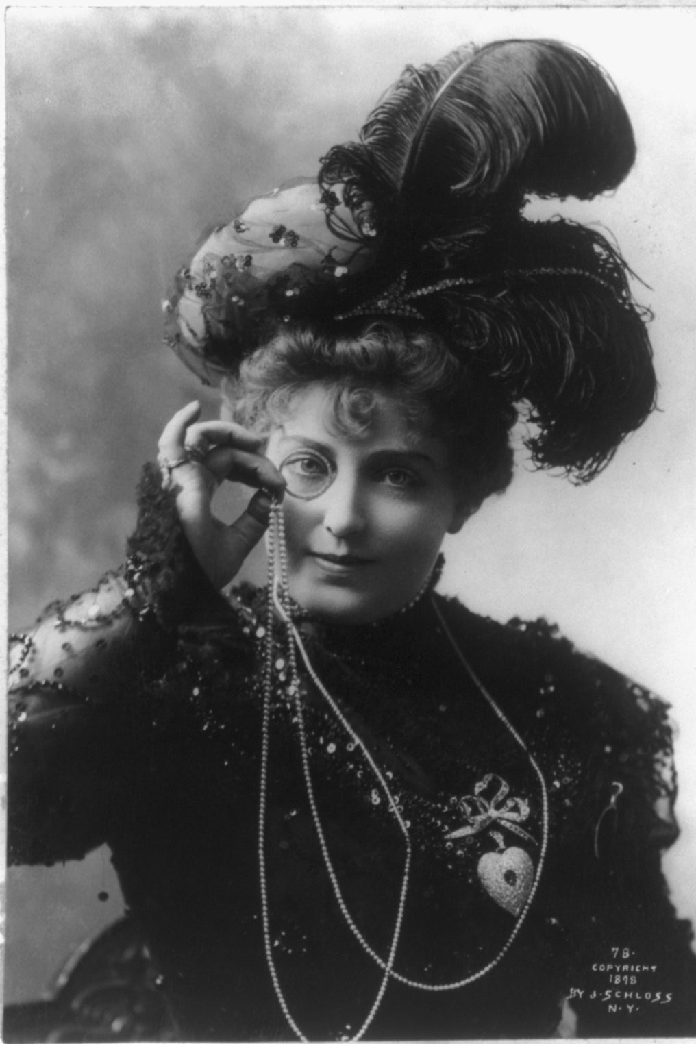 A woman in a monocle and a very feathery hat. 