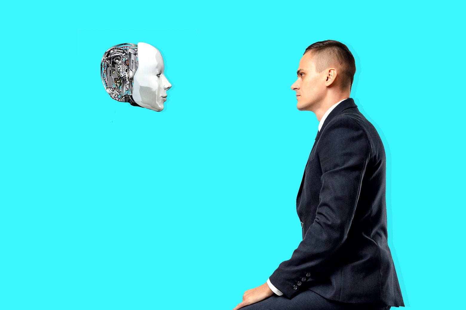 A man in a suit and a robot head stare at each other.