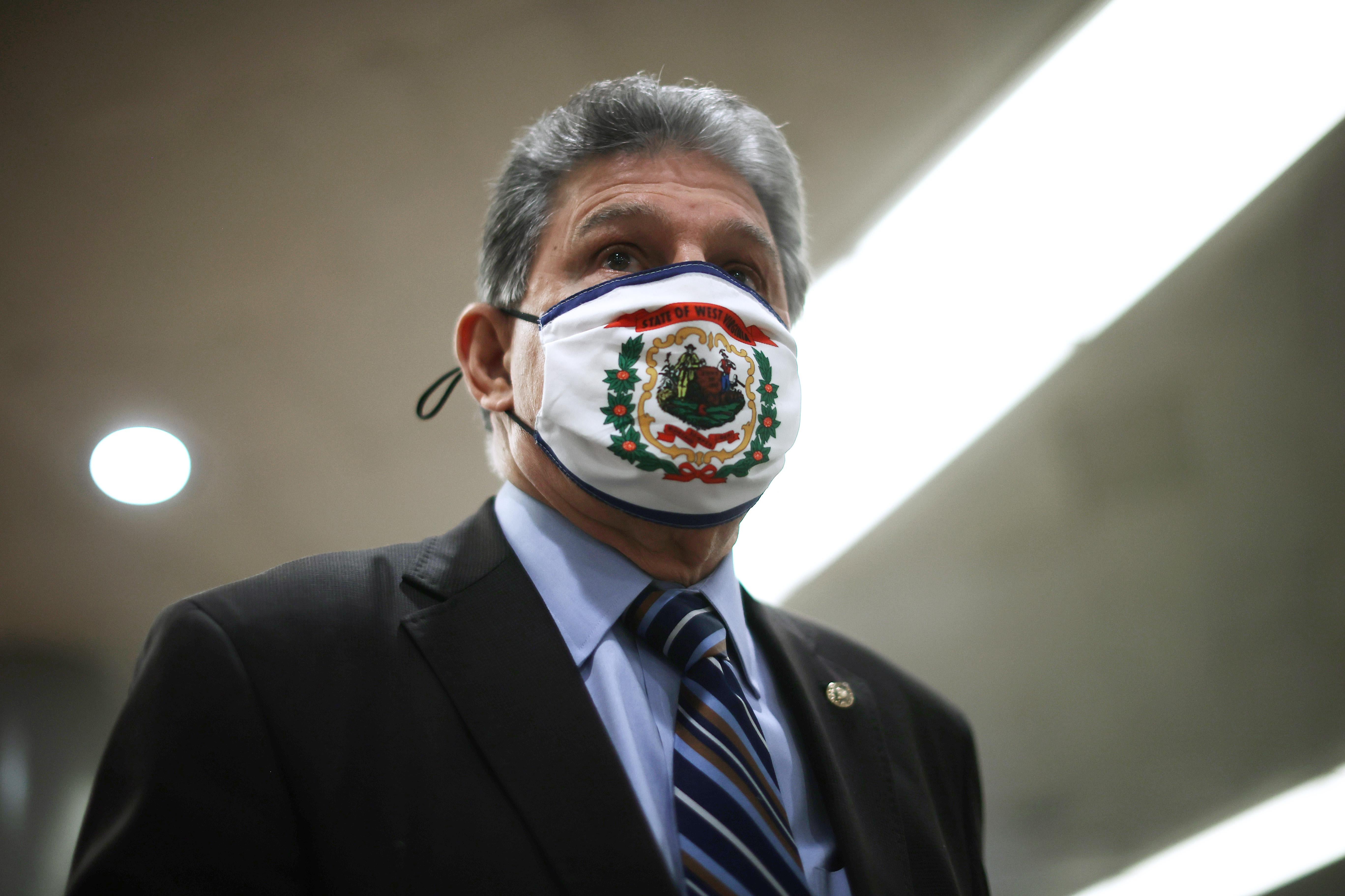Manchin wearing a mask that has the West Virginia coat of arms on it