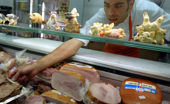Israeli butcher Ronen Solomon arranges a display of non-kosher meats in his delicatessen June 14, 2004 in Ranana in central Israel.