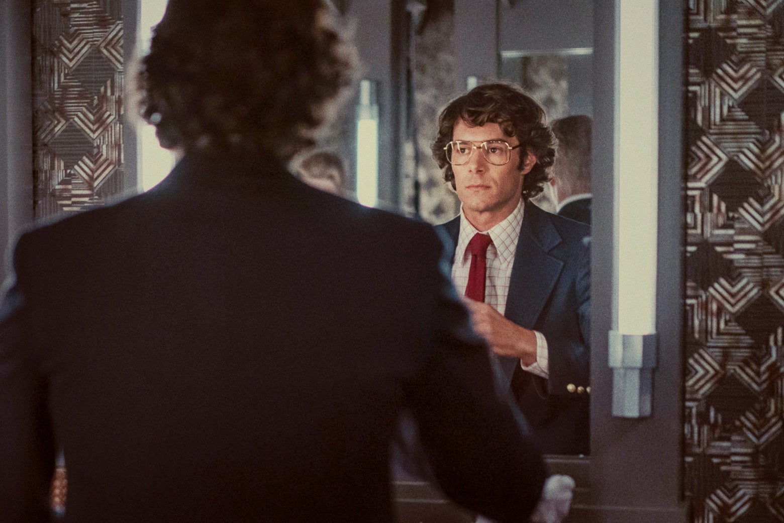 Adam Brody looks into a mirror as Marc Feigen Fasteau.