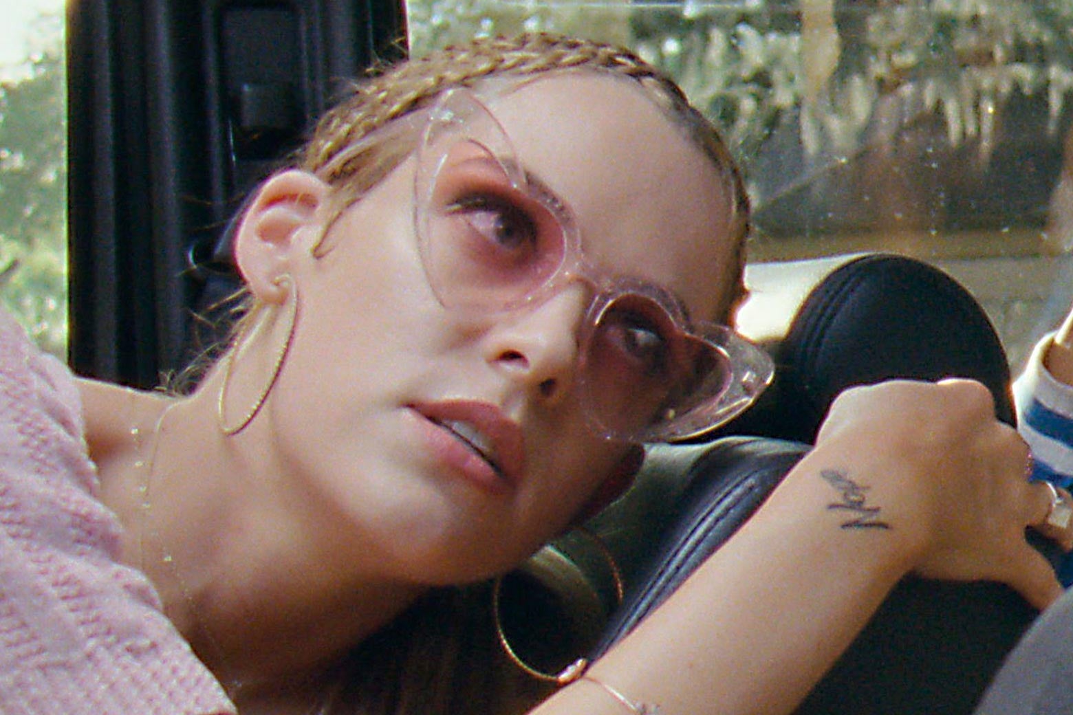 Riley Keough in rose-tinted heart-shaped sunglasses.